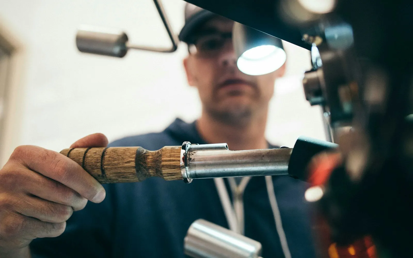 A craftsman shaping a brass part at a workbench lamp